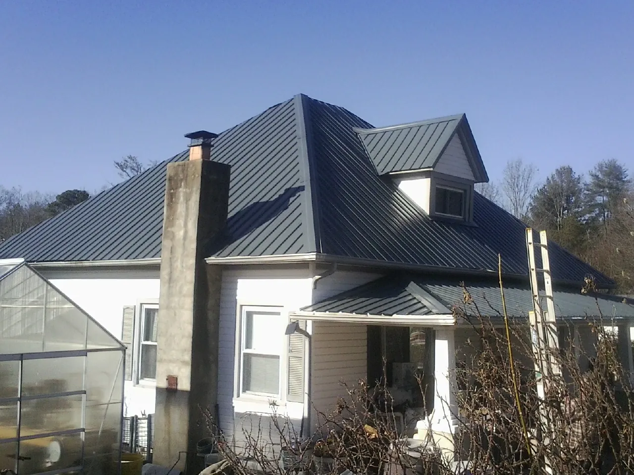 Dark blue standing seam metal roof on a white farmhouse with dormer — Slate & Tile Roof Repair by Roofing Brothers in Troutdale