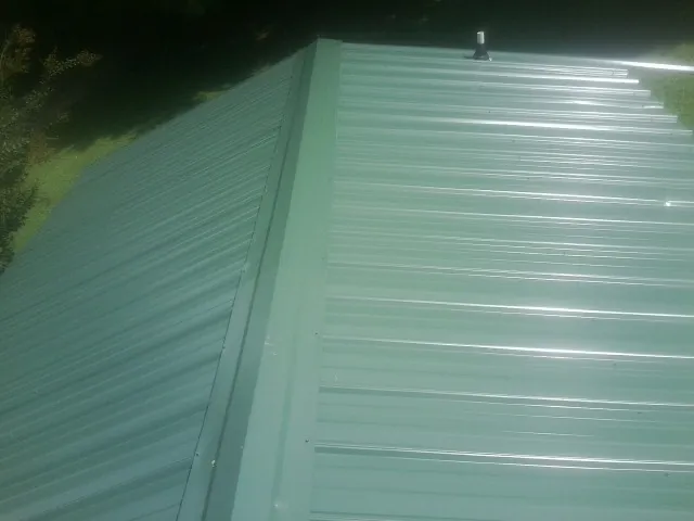 New green metal panels meeting at the ridge of a roof — Flat Roof Repair work by our crew in Troutdale