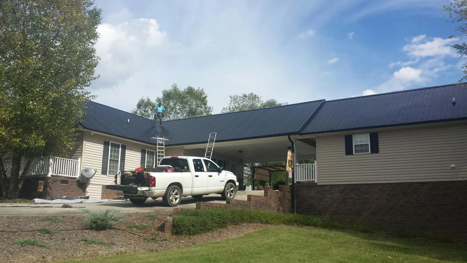 Black metal roof over a home and attached breezeway with ladders set in Troutdale