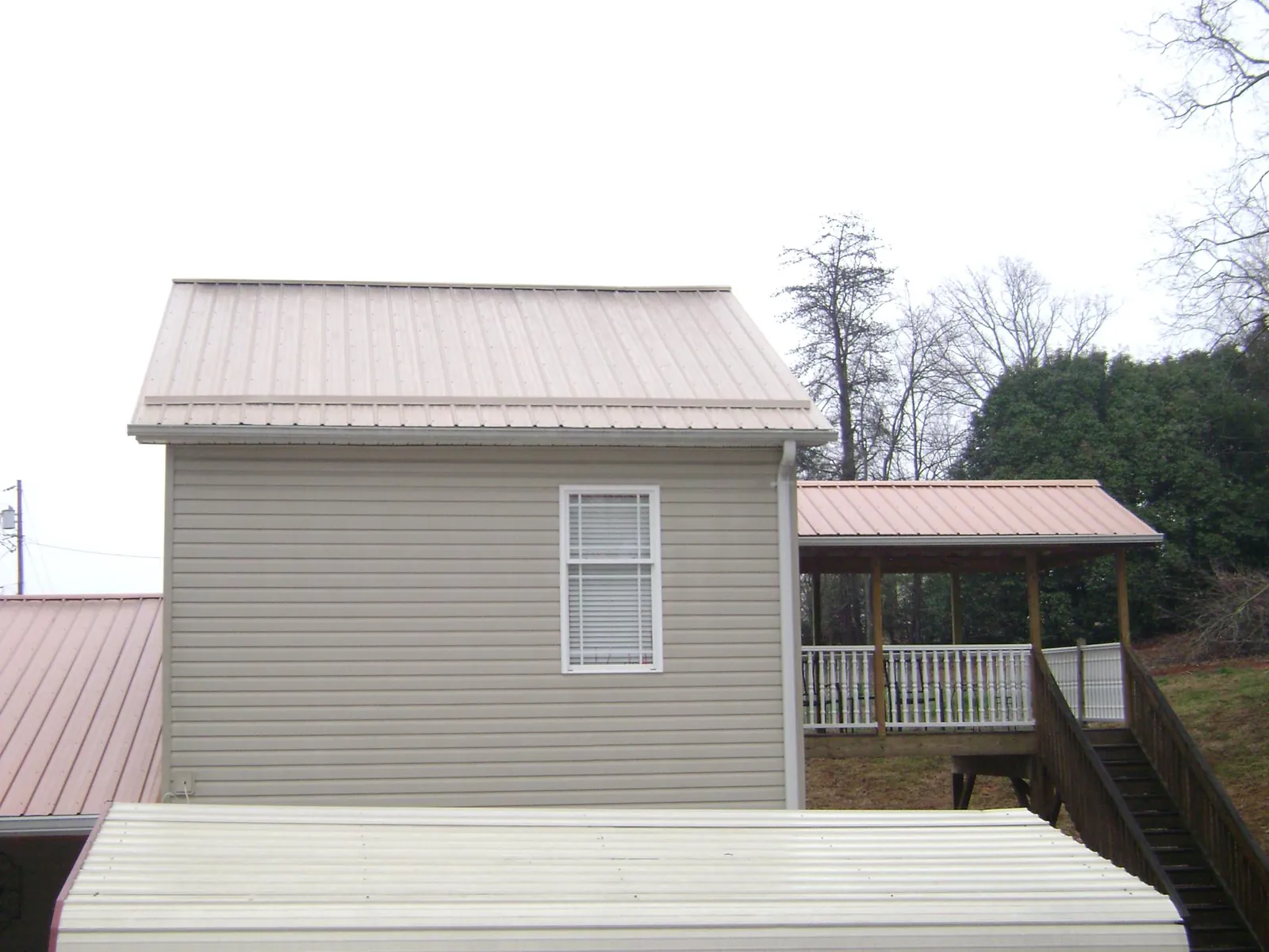 Tan metal roofs on a two story addition and attached porch, from a Roof Replacement job in Troutdale