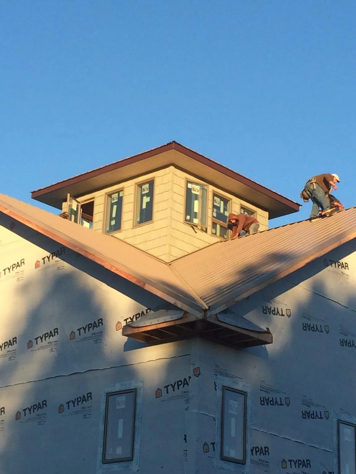 Roofers working around a rooftop cupola on a new metal roof at sunset — Roof Waterproofing in Troutdale by Roofing Brothers